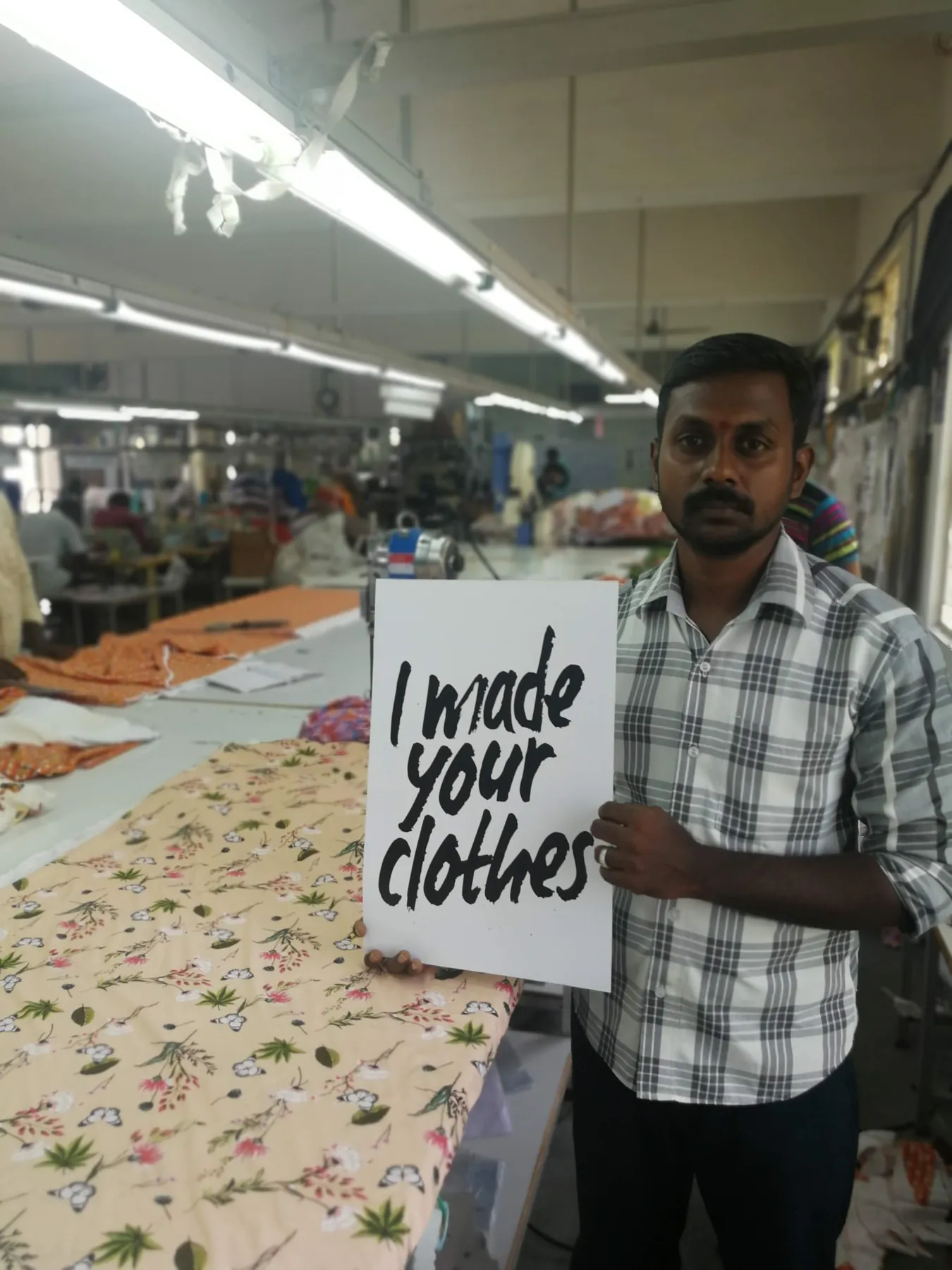 Tailor beside printed fabric on the cutting table at Macrofast's Annur unit