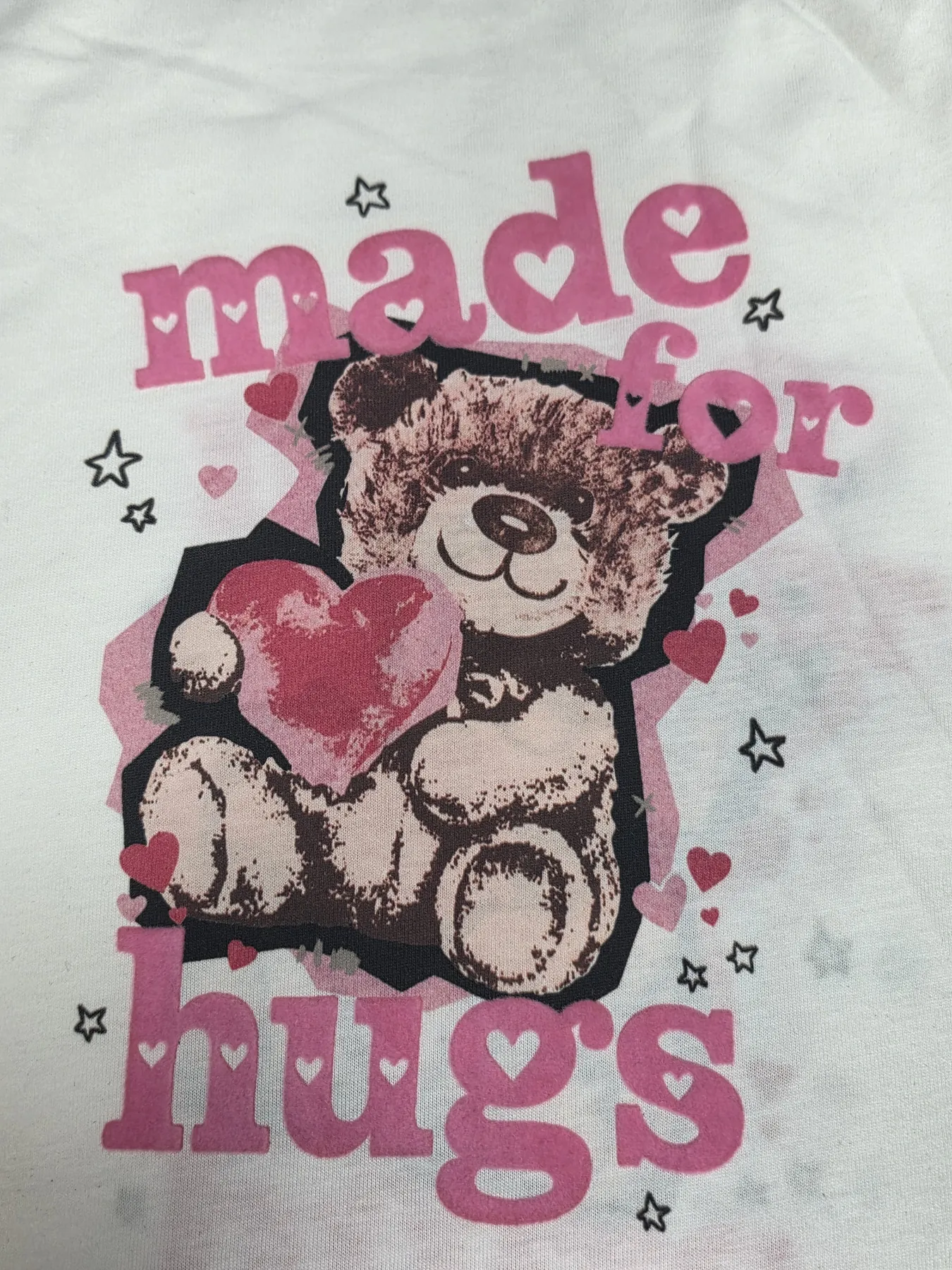 Digital textile print of a teddy bear, hearts and Made for Hugs lettering on kidswear fabric